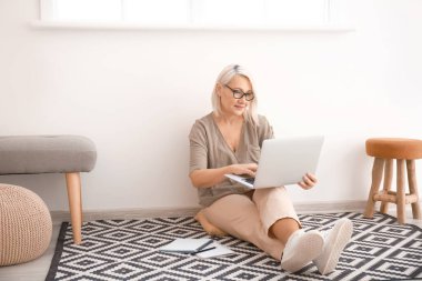 Evde online öğrenim için dizüstü bilgisayar kullanan olgun bir kadın