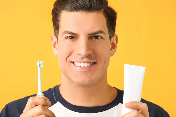 Junger Mann Mit Zahnbürste Und Paste Auf Farbigem Hintergrund — Stockfoto