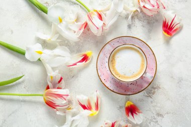 Hafif arka planda bir fincan kahve ve çiçekler.