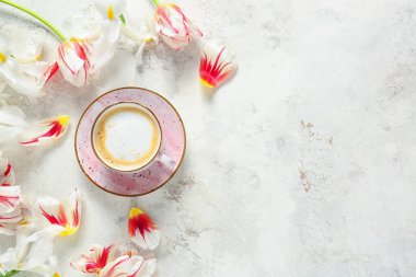 Hafif arka planda bir fincan kahve ve çiçekler.