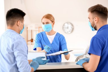 Klinikte hastalarla çalışan kadın resepsiyonist.