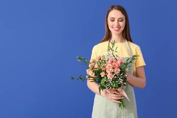 Portrait of female florist with bouquet on color background