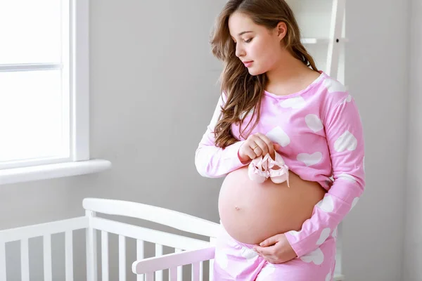 Evde Bebek Ayakkabıları Olan Güzel Hamile Bir Kadın — Stok fotoğraf