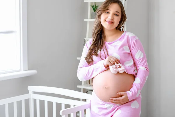 Evde Bebek Ayakkabıları Olan Güzel Hamile Bir Kadın — Stok fotoğraf