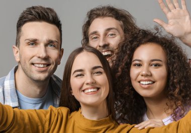 Gri arkaplanda selfie çeken arkadaşlar
