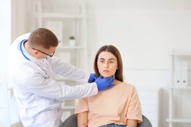 Endokrinolog klinikte genç bir kadının boğazını inceliyor.