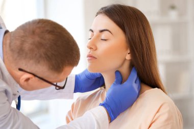 Endokrinolog klinikte genç bir kadının boğazını inceliyor.