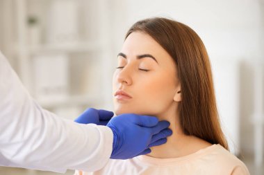 Endokrinolog klinikte genç bir kadının boğazını inceliyor.