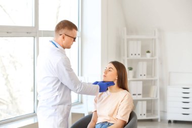 Endokrinolog klinikte genç bir kadının boğazını inceliyor.