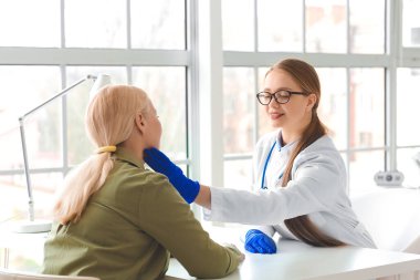 Klinikte tiroid bezi sorunu olan yaşlı bir kadını muayene eden doktor.