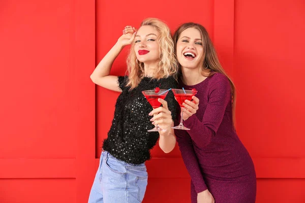 Happy women with cocktails on color background