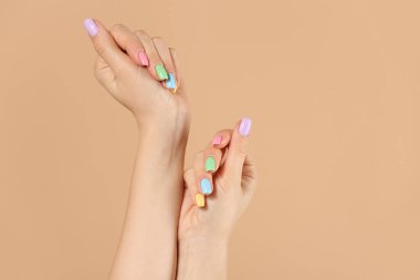 Renkli arka planda güzel manikürlü genç bir kadının elleri