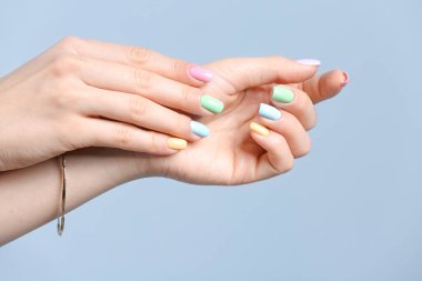 Renkli arka planda güzel manikürlü genç bir kadının elleri
