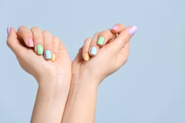 Renkli arka planda güzel manikürlü genç bir kadının elleri