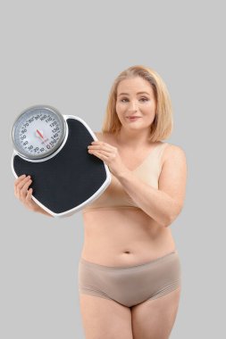 Gri arka planda pulları olan şişman bir kadın. Kilo verme konsepti