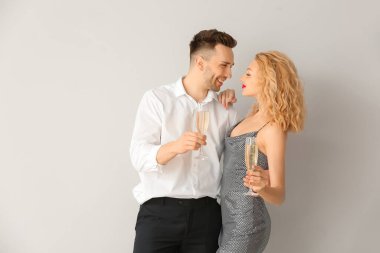 Gri arka planda şampanya kadehleri olan mutlu bir çift.