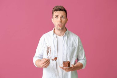 Kirli elbiseli sorunlu bir adam arka planda çikolatalı pasta yiyor.