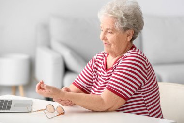 Yaşlı bir kadının evde doktorla görüntülü konuşması.