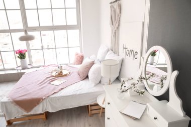 İçinde bahar çiçekleri olan güzel, modern bir yatak odası.