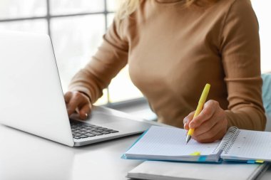 Evde online öğrenim için dizüstü bilgisayar kullanan olgun bir kadın