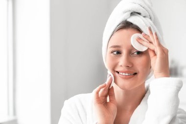 Güzel genç bayan evde makyajı temizliyor.