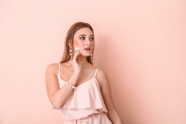 Güzel genç bir kadın makyajı renk arkaplanından kaldırıyor