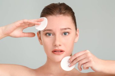 Gri arka planda pamuk pedleri olan güzel genç bir kadın.