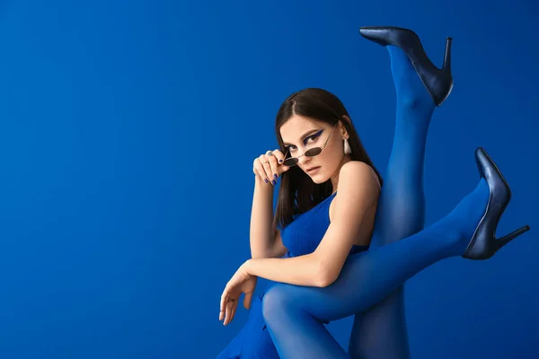 青の背景に女性の足を持つファッショナブルな若い女性の肖像画 — ストック写真
