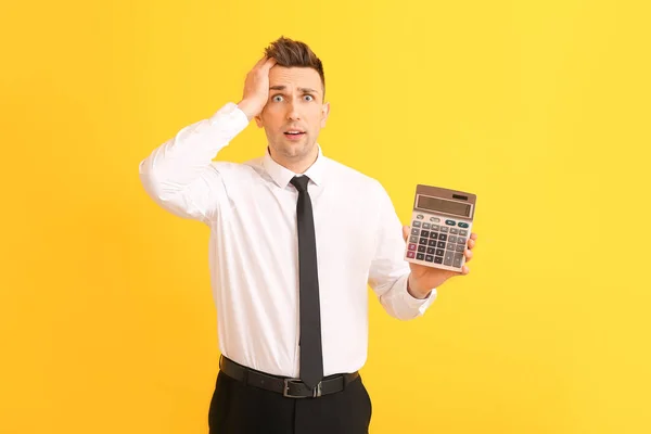 Hombre Joven Estresado Con Calculadora Sobre Fondo Color — Foto de Stock