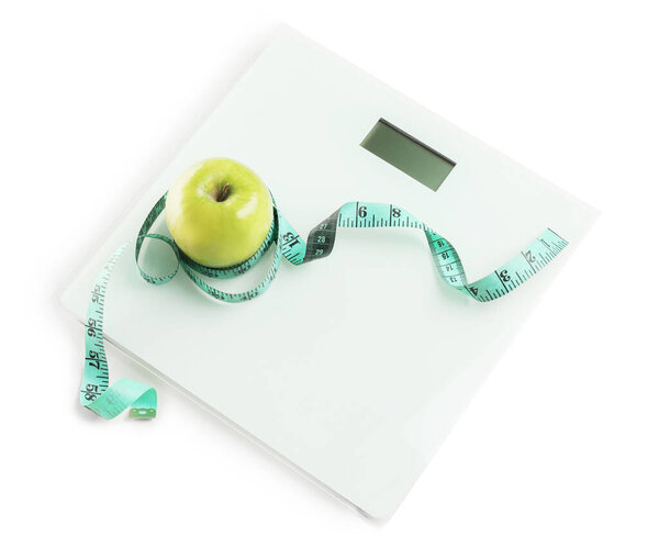 Weight scales with measuring tape and apple on white background. Slimming concept