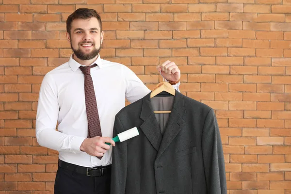 Worker of modern dry-cleaner's on brick background