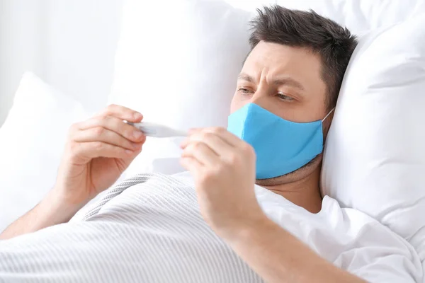 Άνδρας Προστατευτική Ιατρική Μάσκα Που Μετρά Θερμοκρασία Στο Σπίτι — Φωτογραφία Αρχείου