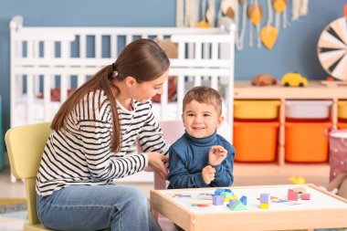 Nanny playing with cute little boy at home