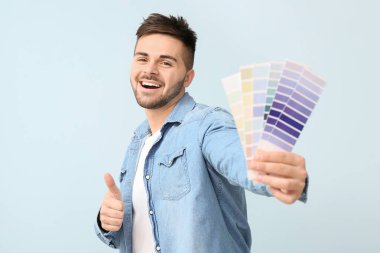 Boya paletli genç adam, arka planda baş parmak hareketi gösteriyor.