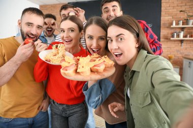 Genç arkadaşlar evde birlikte yemek yaparken selfie çekiyorlar.