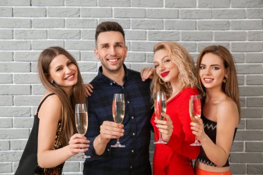 Tuğla arkasında şampanya kadehleri olan mutlu insanlar.