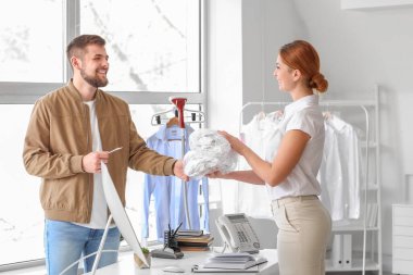 Müşteri modern kuru temizlemeciden kıyafet alıyor.