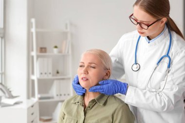 Klinikte tiroid bezi sorunu olan yaşlı bir kadını muayene eden doktor.