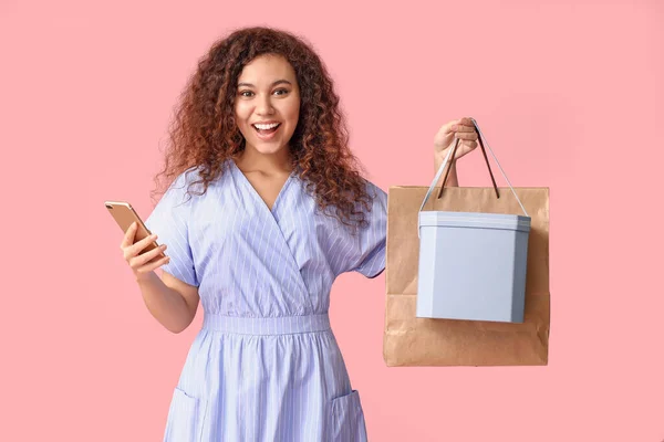 携帯電話 ショッピングバッグ ボックスの色の背景を持つ若い女性 — ストック写真