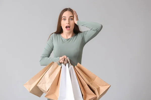 Gri Arka Planda Alışveriş Torbaları Olan Şaşırmış Genç Bir Kadın — Stok fotoğraf
