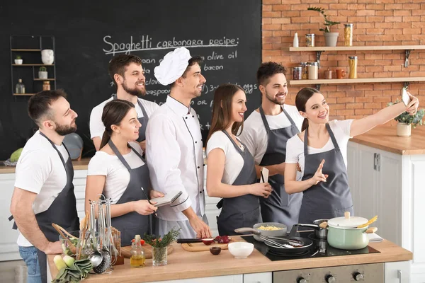 Male chef and group of young people taking selfie during cooking classes