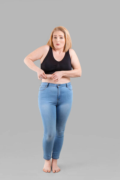 Troubled overweight woman on grey background