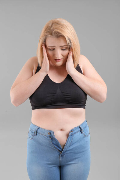 Sad overweight woman on grey background