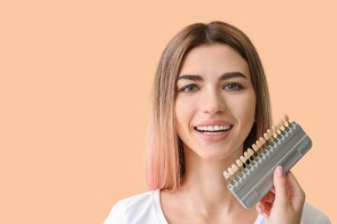 Arka planda diş örnekleri olan güzel genç bir kadın.