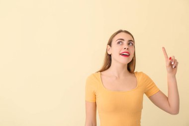 Renkli arka planda işaret parmağı olan güzel bir genç kadın.