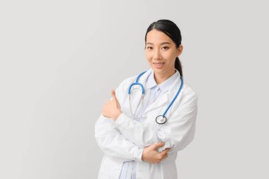Asyalı kadın doktor arka planda baş parmak gösteriyor.