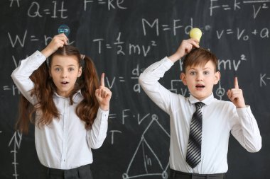 Sınıfta fizik dersinde karatahtanın yanında ampulleri olan sevimli çocuklar.