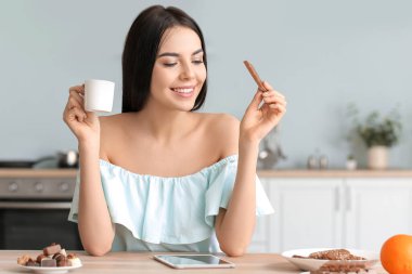 Güzel genç bir kadın mutfakta çikolata yiyor.