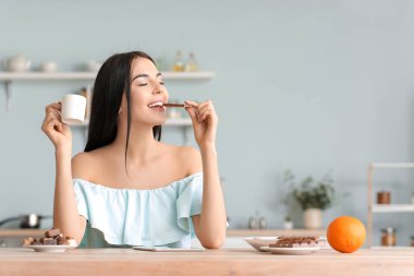 Güzel genç bir kadın mutfakta çikolata yiyor.