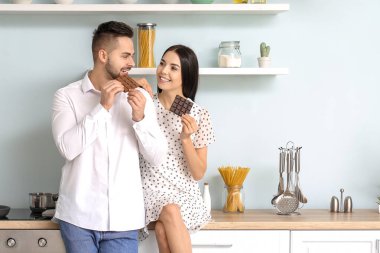 Güzel genç bir çift mutfakta çikolata yiyor.